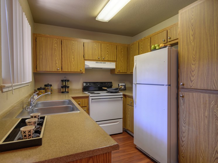 Sink, Wood Cabinets, Dishwasher, Woodinspired Floor, Open Window and Refrigerator/Freezer
